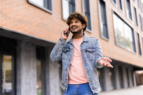 Portrait of bearded young indian man talking on the phone on the street