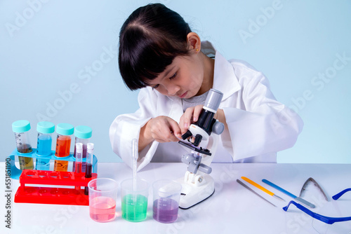 Kid in lab coat learning chemistry in school laboratory, business concepts, experimenting with chemical coloring or marketing planning