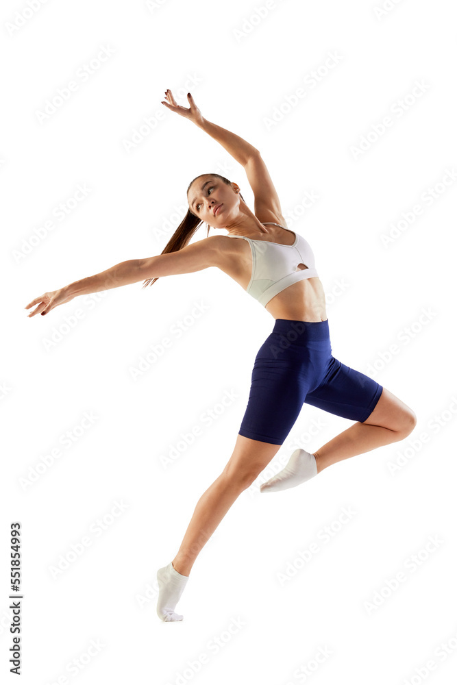 Portrait of young sportive woman training, doing warming up exercises, jumping isolated over white background. Concept of sport, fitness, health