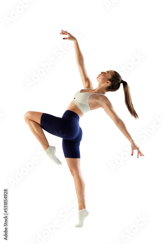 Portrait of young sportive woman training, doing full body exercises, standing on tiptoe isolated over white background. Concept of sport, fitness, health