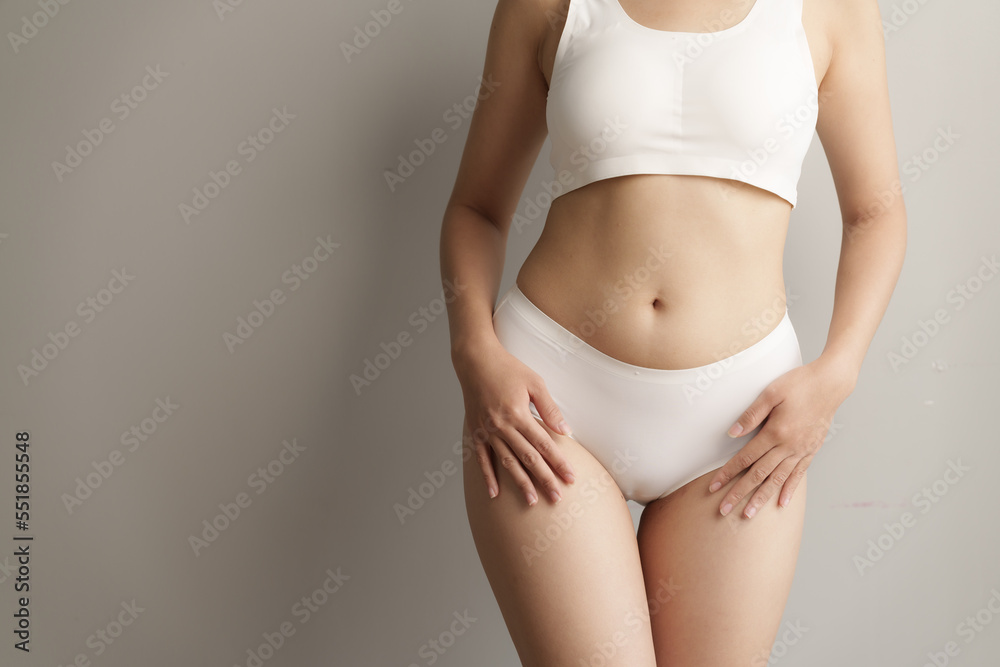 Pretty asian woman wears white lingerie poses against grey background with body care, bra, underwear concept.