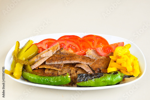 Turkish and Arabic Traditional Ramadan doner kebab with tasty tomato sauce and rice or turkish pilav in white plate on wood table background. ( Pilav ustu doner) photo