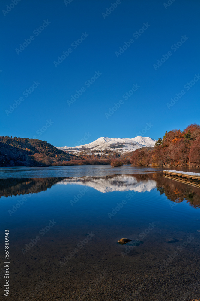 Obraz premium reflet dans le lac Chambon, montagnes enneigées et ciel bleu
