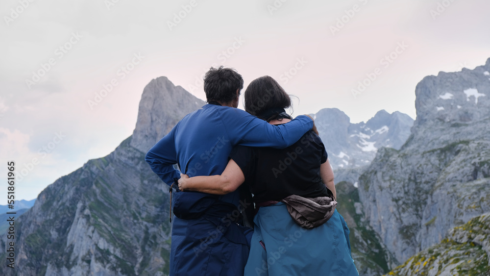 Pareja de adultos abrazados haciendo una ruta en las montañas de Fuente Dé en un día nublado