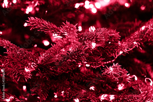 Year 2023 color Viva magenta. A garland of lights on christmas tree