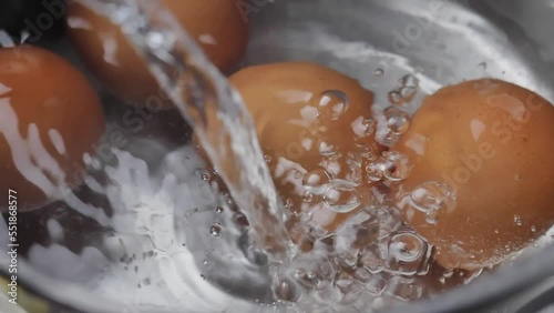 Close up pour the water into the pot for make boiled eggs. Breakfast cooking