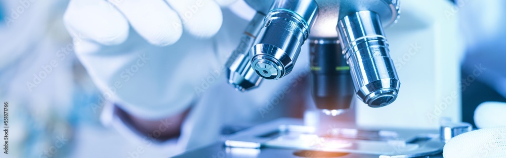 Biological scientist looking at  samples by using microscope doing research for new vaccine in pharmaceutical labolatory - obrazy, fototapety, plakaty 