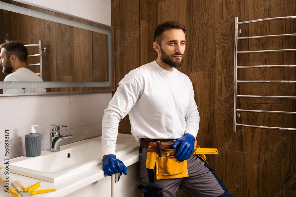 Professional plumber with plunger and instruments near sink.