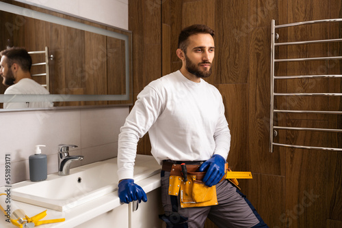 Professional plumber with plunger and instruments near sink.