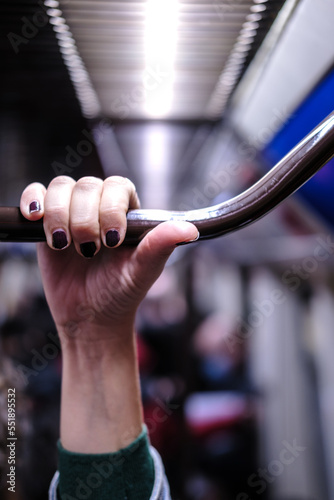 Vertical picture of a hand holding metal bar in a public transport