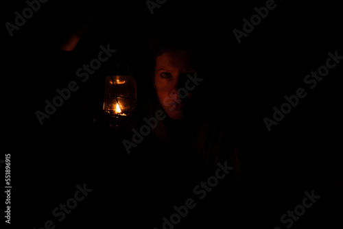 A girl in the dark holds a kerosene lamp, the light © Виктория Котлярчук