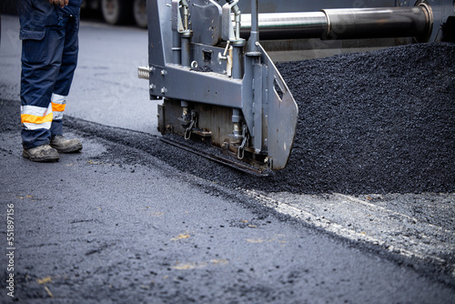 Asphalt paving machine adding new asphalt for road construction.
