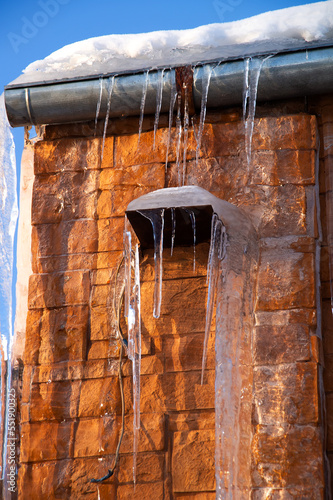 Long icicles on the wall of the building.Ice and icicles on a brick wall.A sunny spring day.
