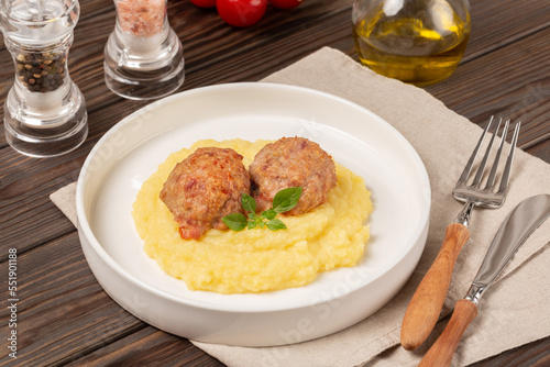 A portion of meatballs with mashed potatoes with parmesan on a white plate, open space