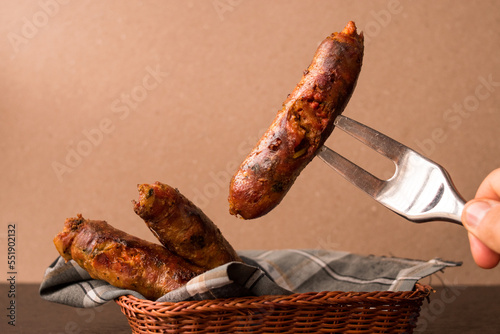 Metal fork taking a fried sausage from a basket