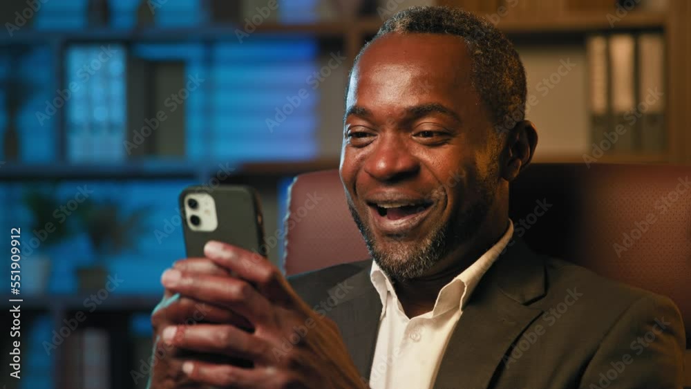 Close-up african american man looking at phone screen playing mobile game browsing social network surprised excited joyful businessman winner gets good deal notice says wow winning rejoices in success