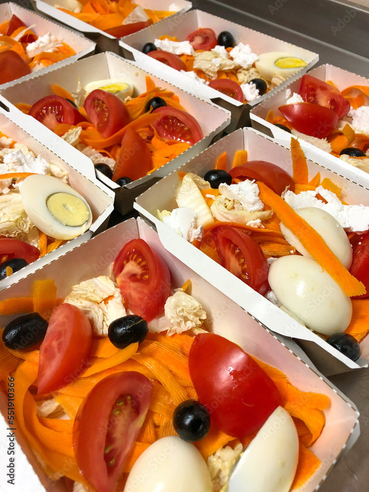 Healthy salad with carrots, eggs, tomatoes, olives, Chinese cabbage and feta cheese in take away boxes. Food delivery concept.