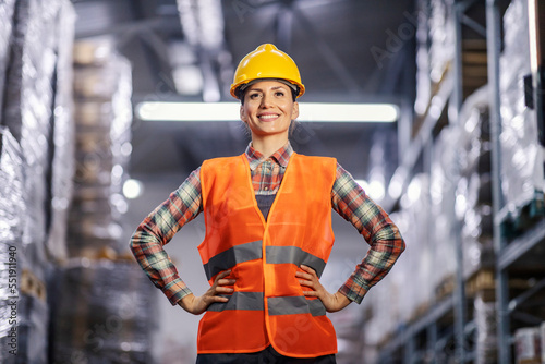 A happy storage worker in full protective uniform posing in facility.