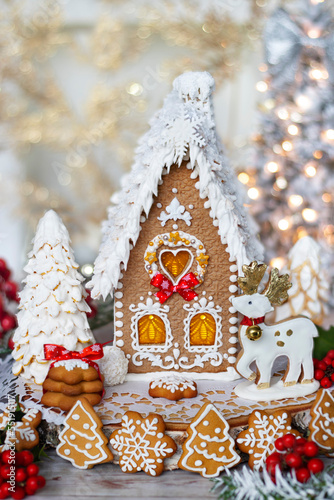 Красивый пряничный домик и рождественские печенья на столе с праздничным декором. Крупный план. Место для текста. 