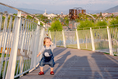 Walk in the park for a small child. Summer day in nature. Toddler walks on a wooden bridge