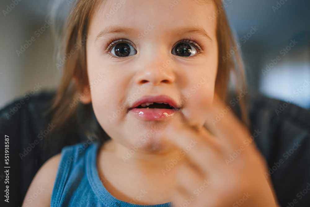 Close-up portrait of a young dirty baby girl eating in high chair. Healthy eating. Close-up portrait of a young dirty baby girl eating in high chair. Healthy eating.