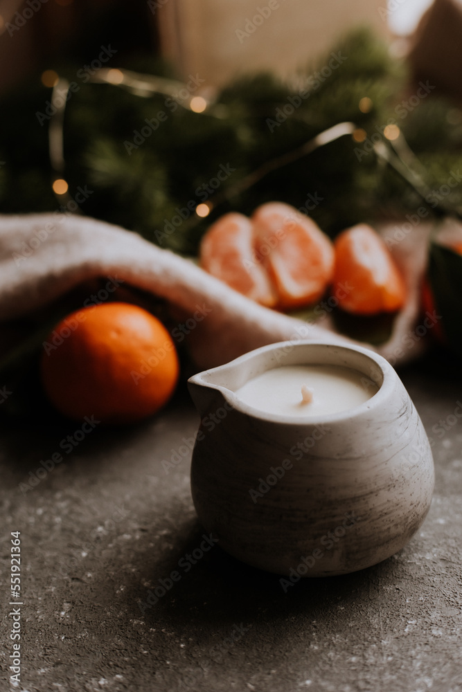 handmade scented candle on a gray concrete background next to tangerines. Gifts for Christmas. New Year's comfort at home