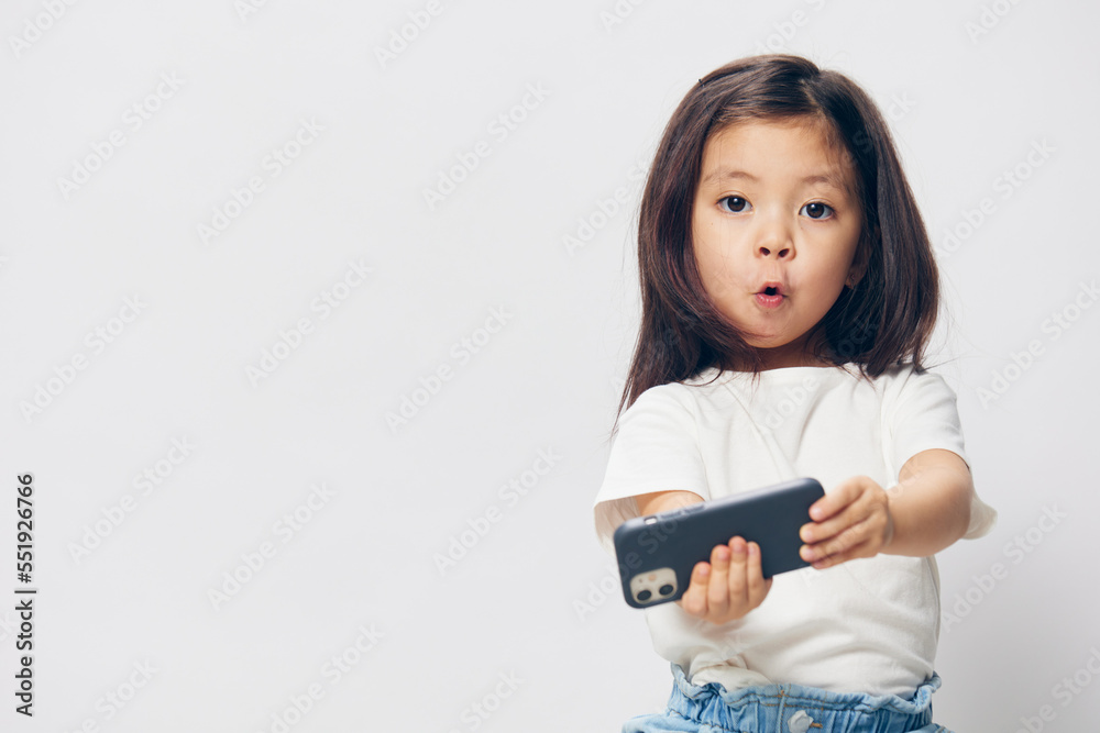 funny, cheerful girl makes a funny face while standing with a fashionable smartphone in her hands and taking a selfie. funny, cheerful girl makes a funny face while standing with a fashionable smartphone in her hands and taking a selfie.