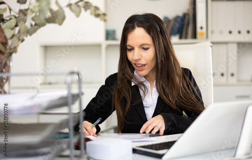 Woman bookkeeper doing paperwork during workday in office.