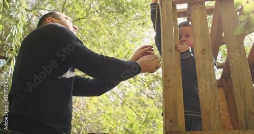 happy father and son building a tree house in the garden