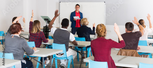 Smiling male teacher giving presentation for students in lecture hall