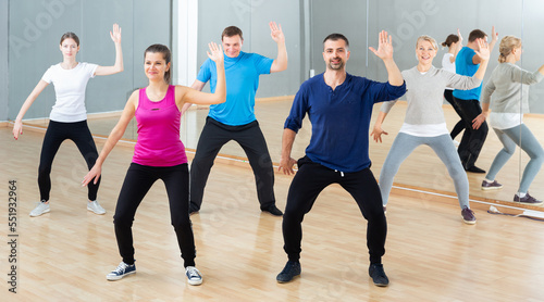 Group of adult people training in gym, doing aerobics exercises