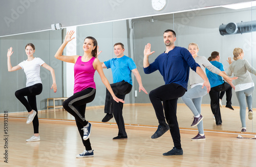 Fototapeta Naklejka Na Ścianę i Meble -  Smiling females and males doing Zumba dance workout during group classes in fitness center