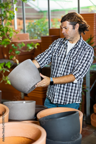 Portrait of handsome man choosing pots for flowers and trees in gardening market