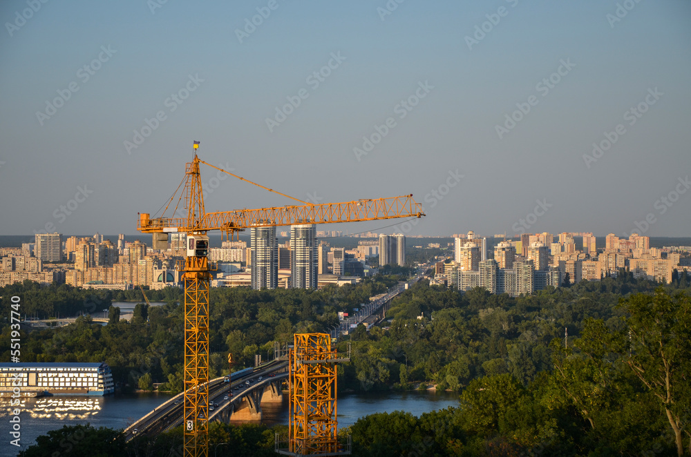 Construction crane on the background of residential buildings of the left bank of the Dnipro river in Kyiv, Ukraine
