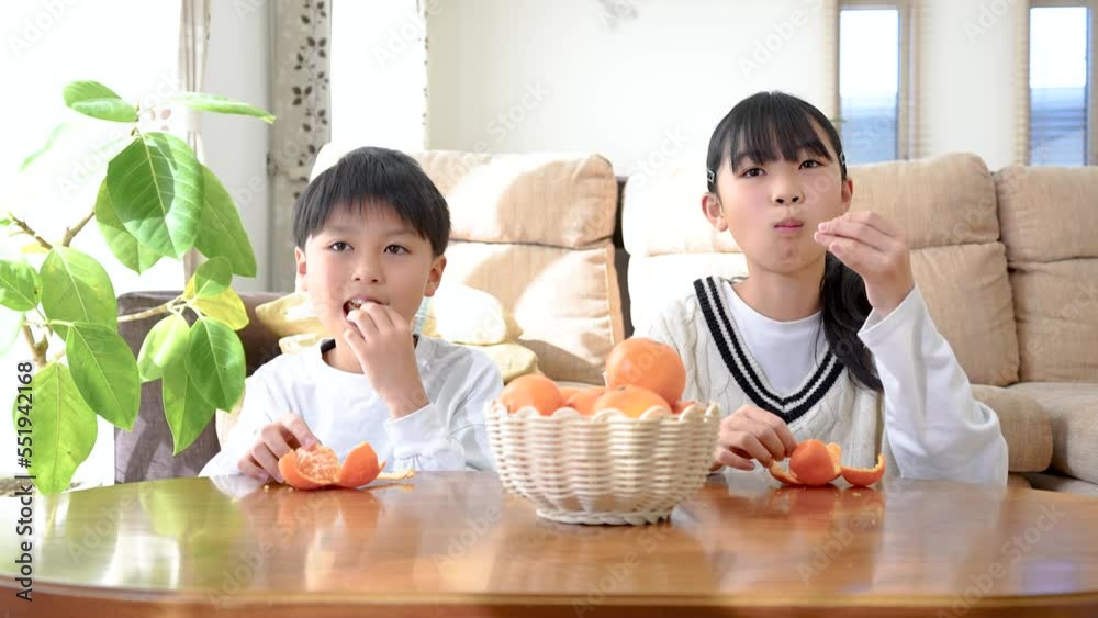 リビングのこたつでみかんを食べているアジア人の子供 リビングのこたつでみかんを食べているアジア人の子供
