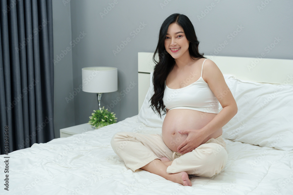 happy pregnant woman stroking her belly on bed happy pregnant woman stroking her belly on bed
