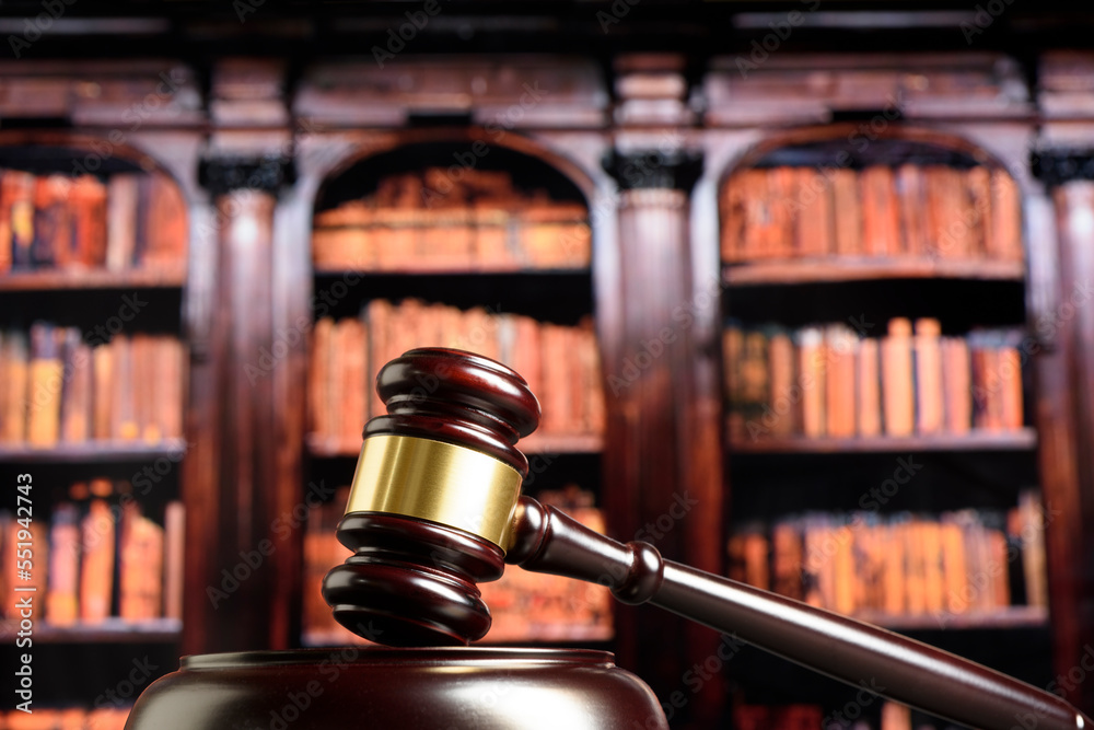 Close up of wooden judge gavel. Blury book library background Close up of wooden judge gavel. Blury book library background