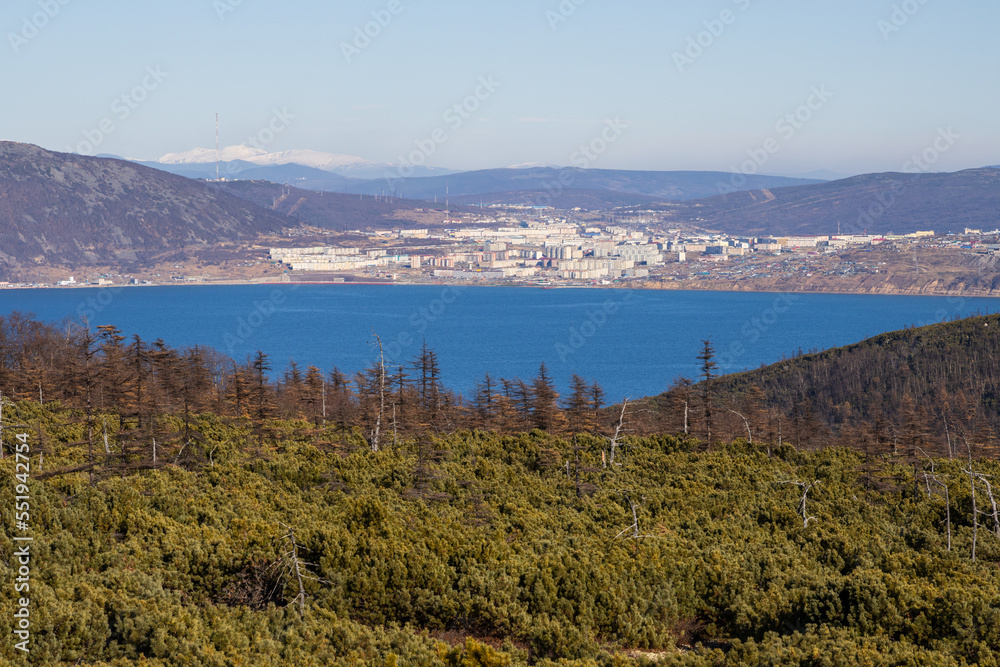 View from the hill to the sea bay and the port city. Autumn landscape. Beautiful nature of Siberia and the Russian Far East. Travel in the Magadan region. Surroundings of the city of Magadan, Russia.