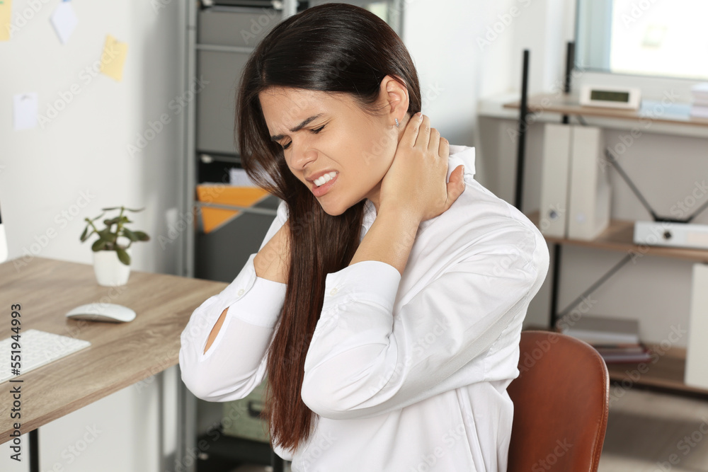 Young woman suffering from neck pain in office Young woman suffering from neck pain in office