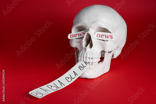 Information warfare concept. Saying useless nonsense as result of media propaganda influence. Human skull with paper cards on red background photo