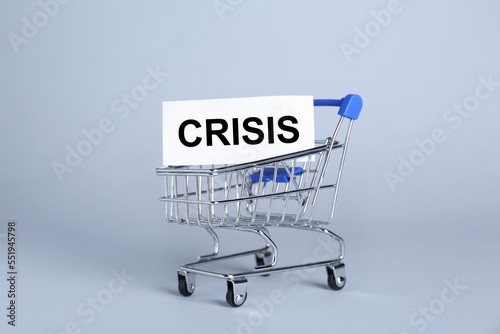 Mini metal cart and word Crisis on light background