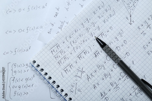 Notebook with different mathematical formulas and pen, top view