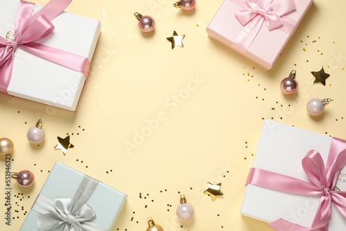 Frame of beautiful gift boxes and Christmas balls on beige background, flat lay. Space for text