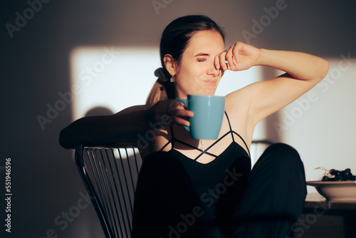 Sleepy Woman Rubbing her Eyes Having Coffee in the Morning. Somnolent girl feeling drowsy and tired all the time
 photo
