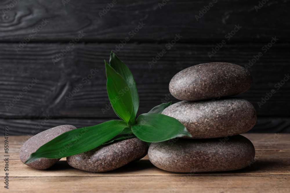 Spa stones with bamboo leaves on wooden table. Space for text Spa stones with bamboo leaves on wooden table. Space for text