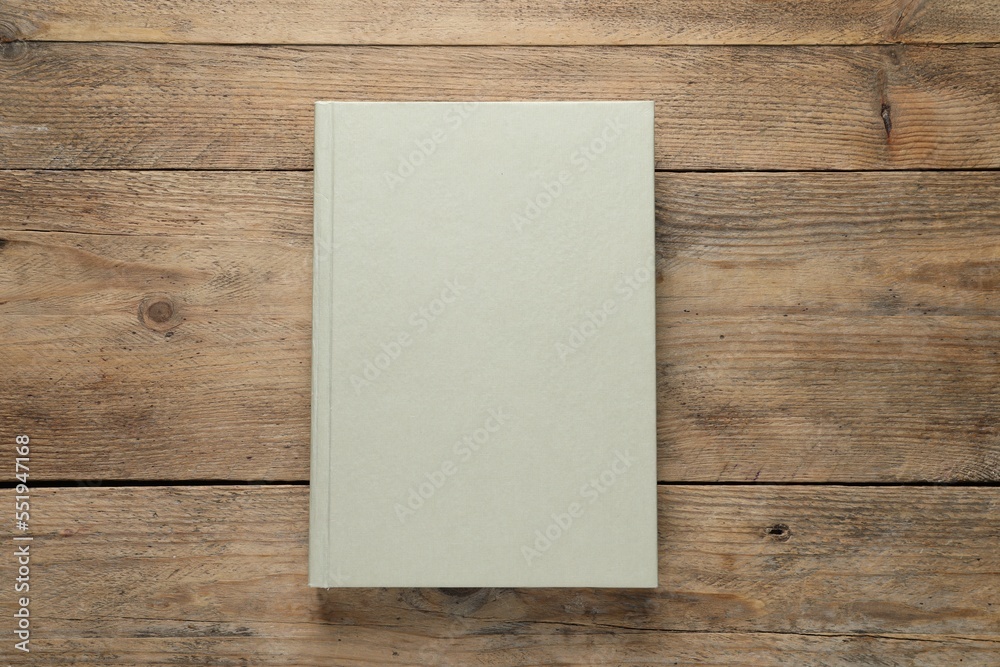 Closed hardcover book on wooden table, top view Closed hardcover book on wooden table, top view