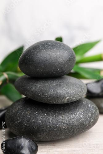 Stacked spa stones and bamboo on white wooden table, closeup