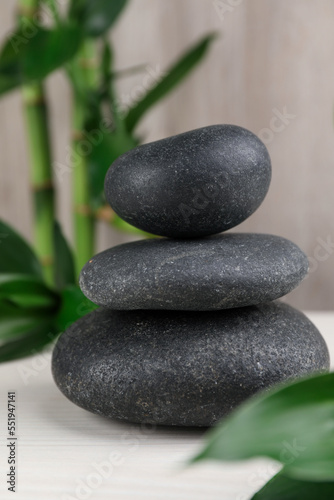 Stacked spa stones and bamboo on white wooden table  closeup