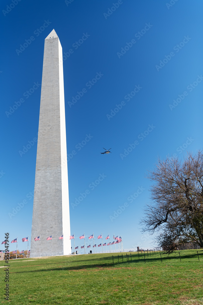 Obraz premium washington dc. A helicopter flies over George Washington's monument on a sunny day with a blue cloudless sky background.