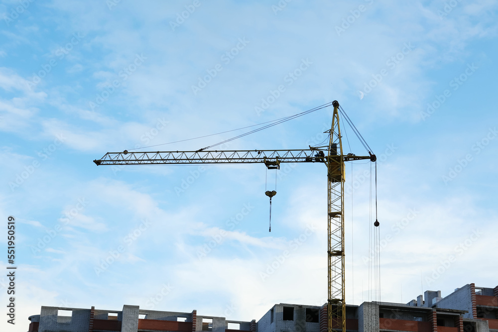 Construction site with tower crane near unfinished building